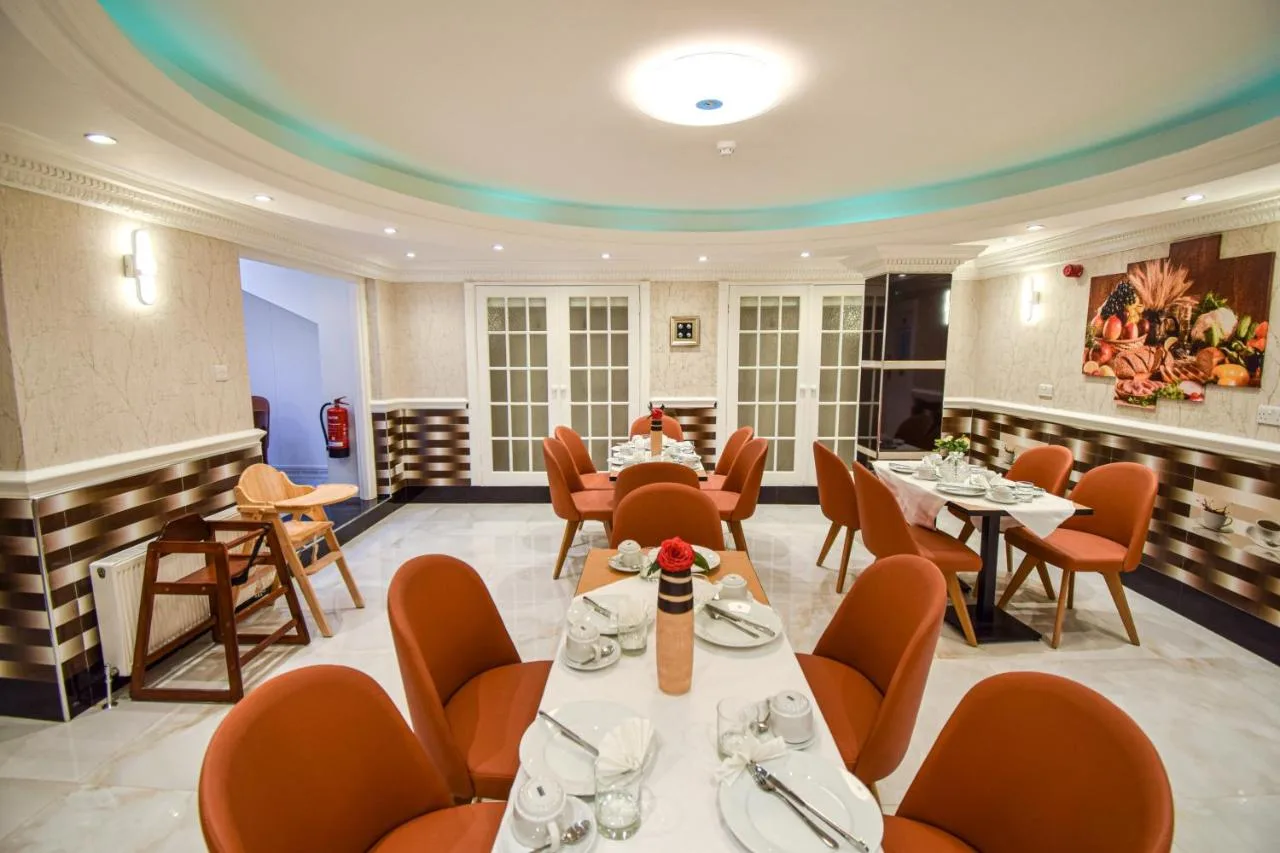 a restaurant with tables and chairs in a room at Pembridge Palace Hotel in London