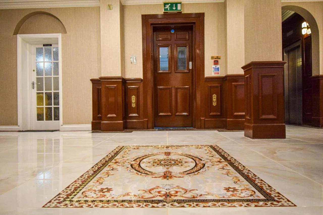 a lobby with a rug in the middle of a building at Pembridge Palace Hotel in London