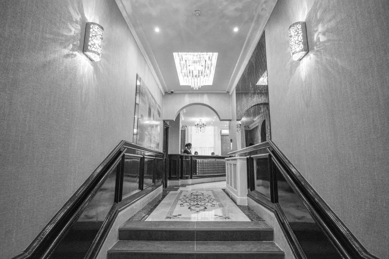 a hallway with stairs and a person walking down it at Pembridge Palace Hotel in London